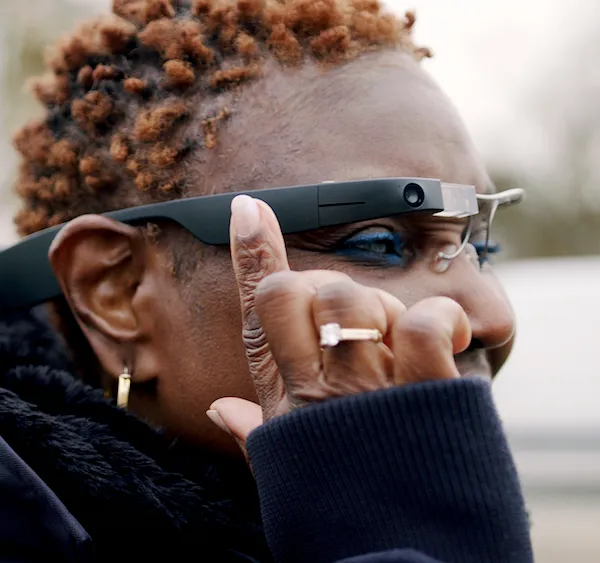 A woman wearing the Envision glasses and tapping it.