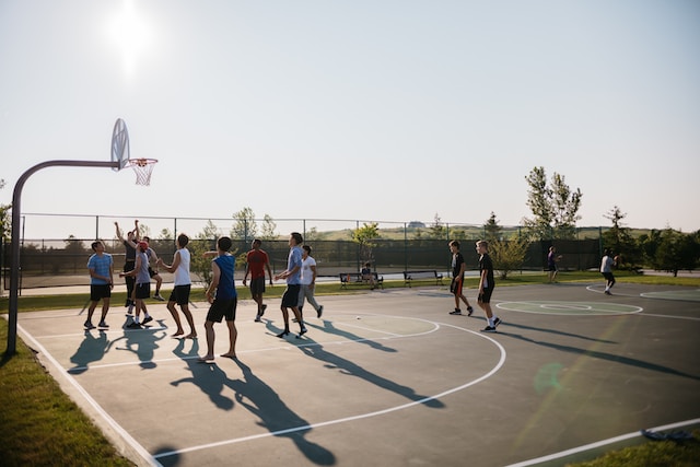 A group of teenage boys playing basketball on an outdoor court.